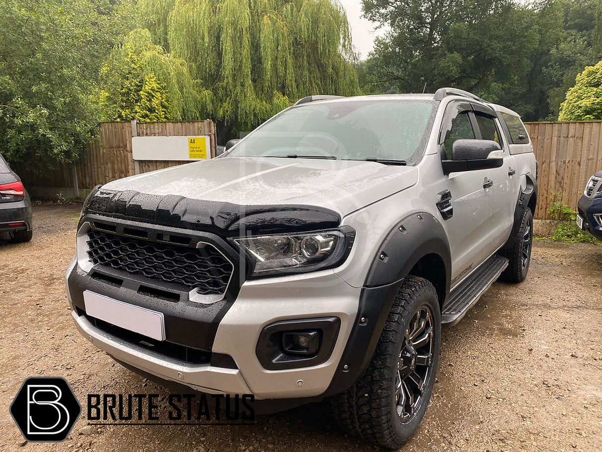 Ford Ranger 2019-2022 T8 Black Grille (Wildtrak Only), featuring a smooth black finish, installed on a silver truck parked on a dirt road.