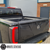 Nissan Navara NP300 2015-2022 Tailgate Cladding Cover/Protector, shown on a parked black truck, offers durable, UV-resistant ABS plastic protection.