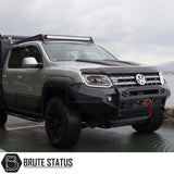 VW Amarok 2017-2022 Heavy Duty Winch Front Bumper, featuring a matte black finish, LED lights, and winch space, parked on a dock.