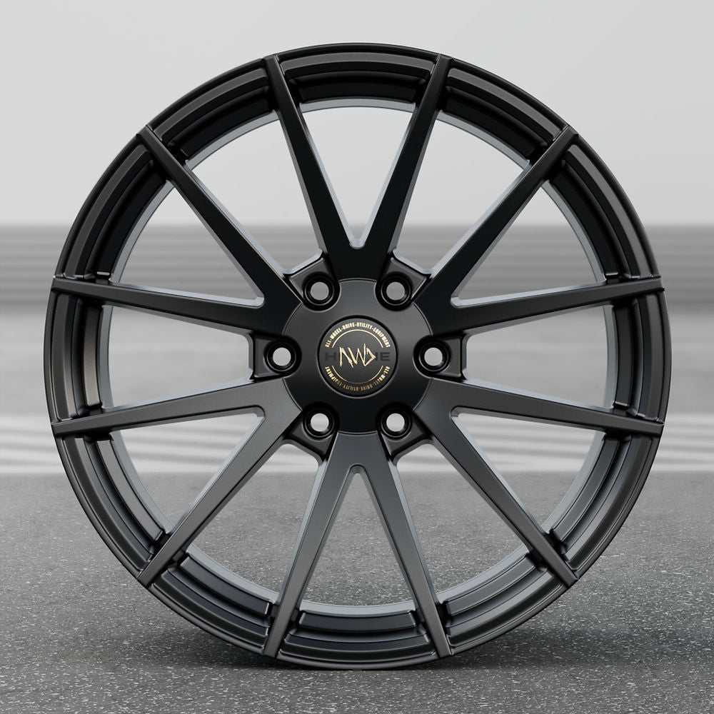 Hawke Wheels Hekla in Matt Black, alloy rim featuring a gold logo, showcased on a road; designed for 6-lug fitments in pick-up truck optimizations.