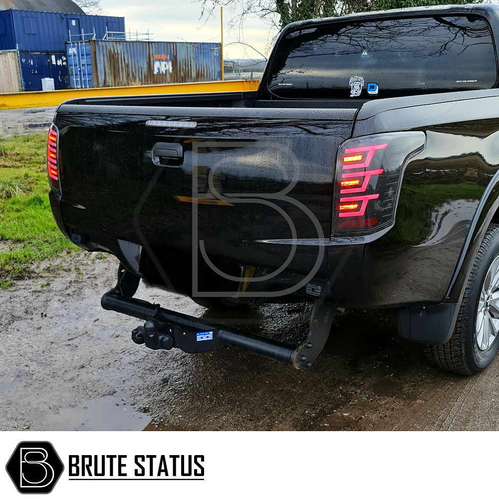 Mitsubishi L200 2015-19 LED Tail Lights, featuring clear lenses and white accents, installed on a black truck, enhancing its rear with stylish, sequential indicators.