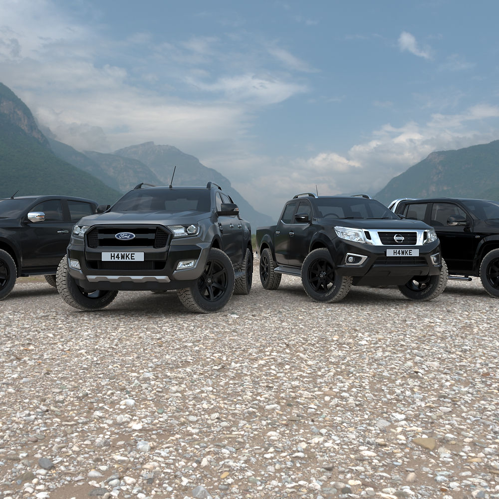 Hawke Wheels Summit in Matt Black, showcased on black trucks parked on rocky terrain, highlighting their robust design for off-road vehicles.